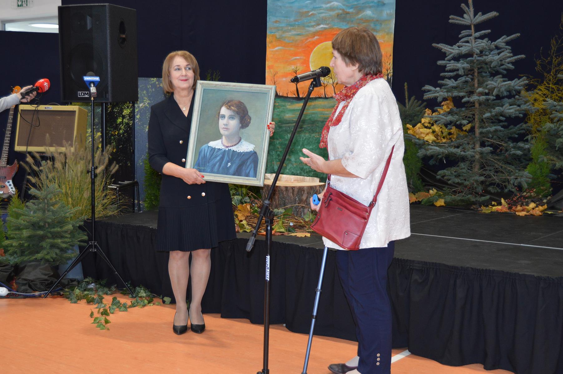 Na zdjęciu widać panią dyrektor szkoły w Bielisze- Małgorzatę Jakubiak, która przyjmuje obraz z rąk rodziny Tereski. Jest to portret z wizerunkiem Teresy Grodzińskiej