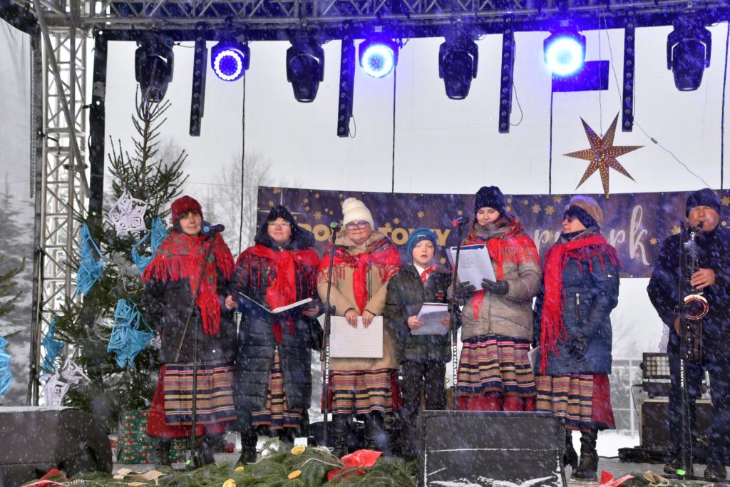 Na scenie występuje zespół ludowy „Kalina”. Panie mają założone tradycyjne kolorowe chusty, pośrodku jest chłopiec oraz z prawej strony Pan grający na saksofonie.