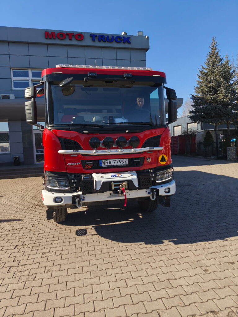 Na tle budynku czerwony wóz strażacki OSP Dąbrówka Podłężna