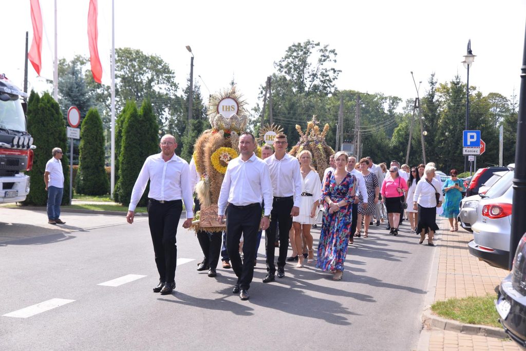 Przemarsz korowodu dożynkowego. na pierwszym planie mężczyźni niosący wieniec.