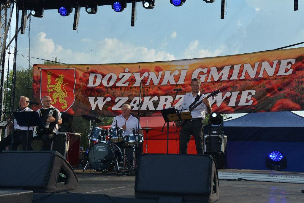 Scena - występ kapeli ludowej, 4 mężczyzn, wszyscy z instrumentami muzycznymi.