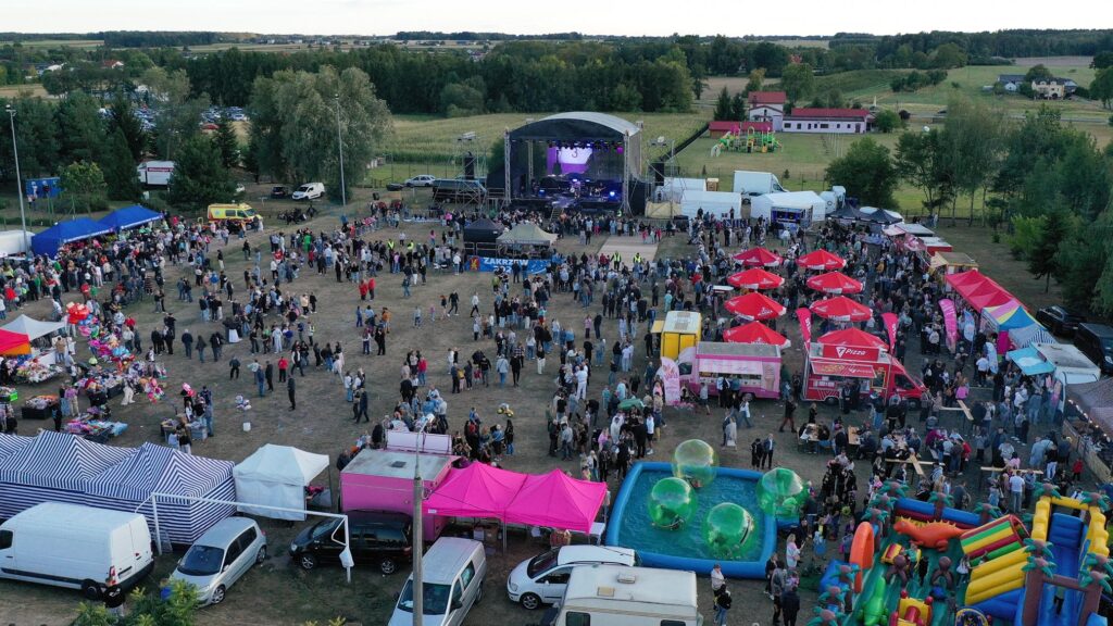 Z góry widać duża grupę ludzi, stoiska wystawowe i w oddali scenę.