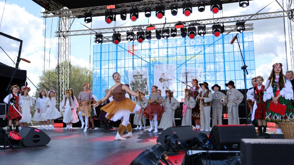 Na scenie dziecięcy zespół ludowy - w barwnych, kolorowych strojach.