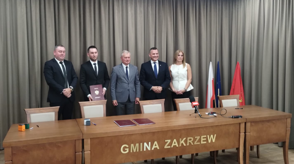 Uczestnicy oficjalnego podpisania umowy pozują do wspólnego zdjęcia w sali konferencyjnej Urzędu Gminy Zakrzew